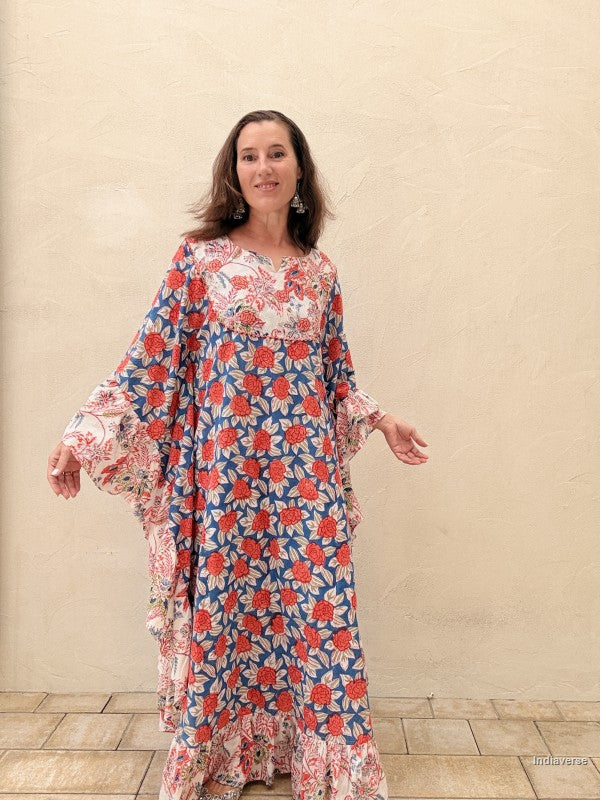 woman wearing a long kaftan dress with red rose design standing in front of a beige wall