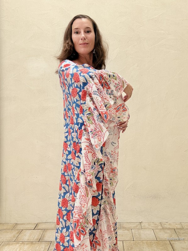 woman wearing a long kaftan dress with red rose design standing in front of a beige wall