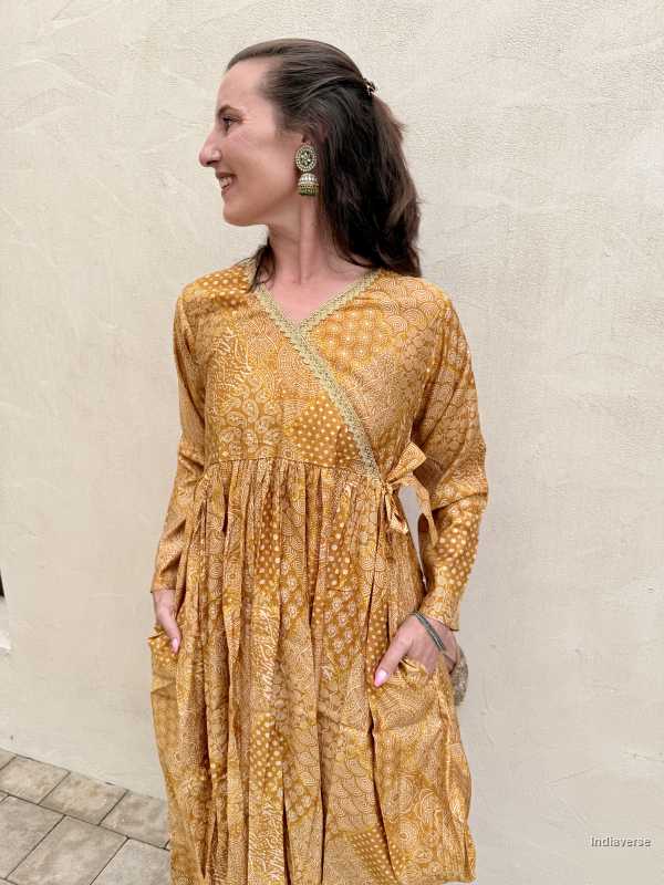 Woman wearing a long-sleeve yellow dress with a pattern against a light background