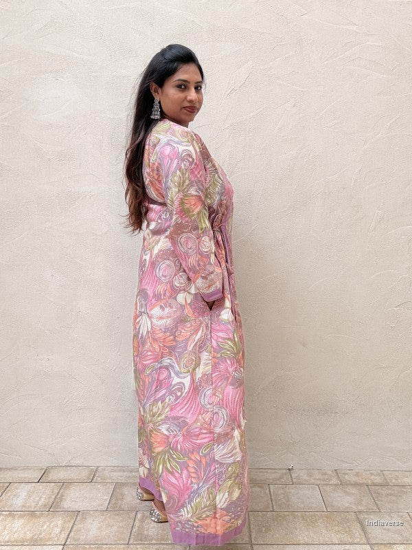 Woman wearing a pink floral dress against a beige wall.