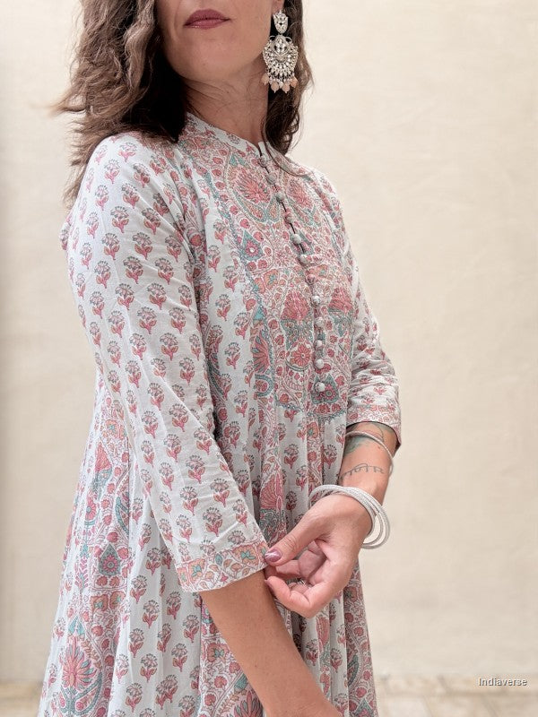 A woman wearing a light beige kurta with a pink and green floral block print, featuring three-quarter sleeves and a buttoned neckline.