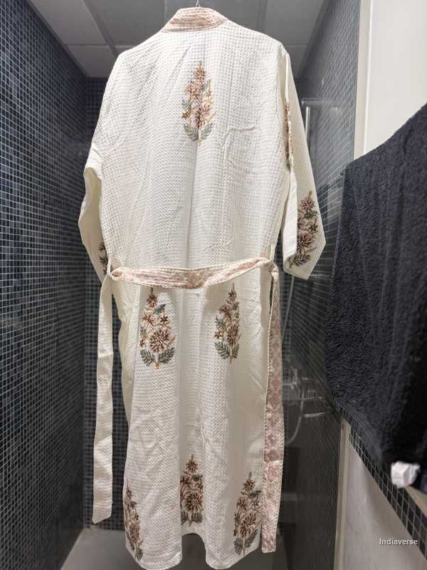 White embroidered robe hanging against a tiled wall