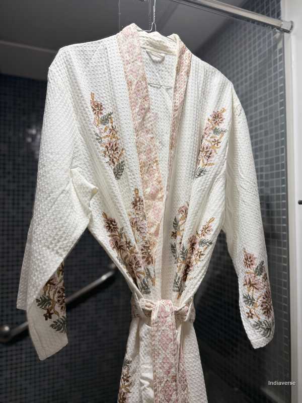 White embroidered robe hanging on a rack against a dark background