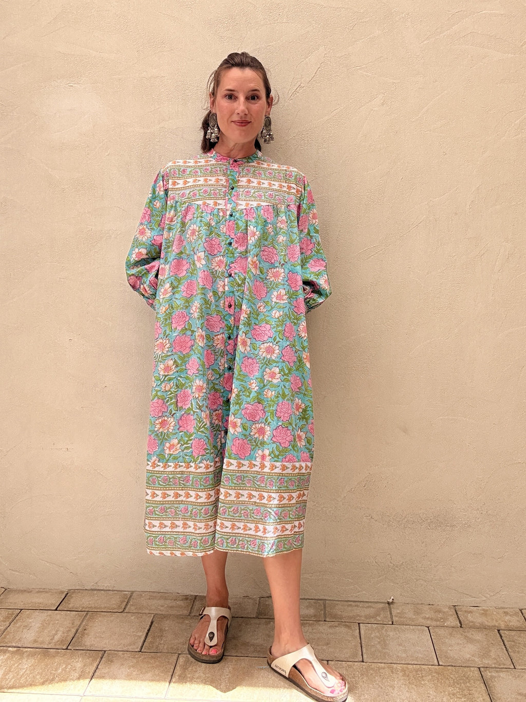 Woman wearing a floral dress against a beige wall.