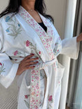 Woman wearing a white floral embroidered robe indoors.