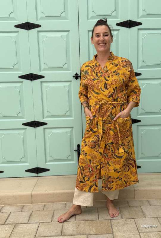 Woman wearing a yellow waffle cotton bathrobe with floral print, standing barefoot in front of a mint green door