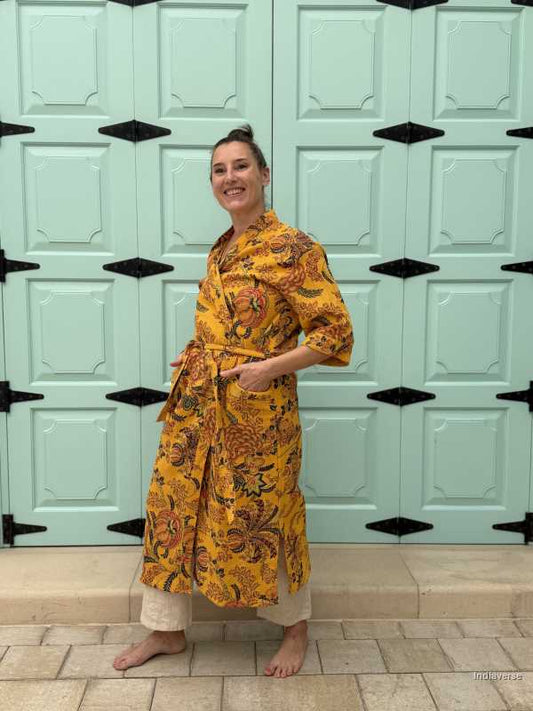 Woman wearing a yellow waffle cotton bathrobe with floral print, standing barefoot in front of a mint green door