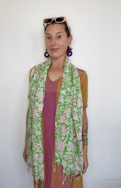 woman standing in front of a while wall wearing a green and white floral cotton scarf