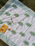 White fabric with green palm tree patterns on a grassy background