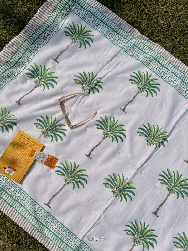 White fabric with green palm tree patterns on a grassy background