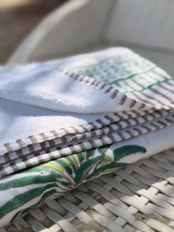 Stack of folded fabric with green and brown patterns on a woven surface
