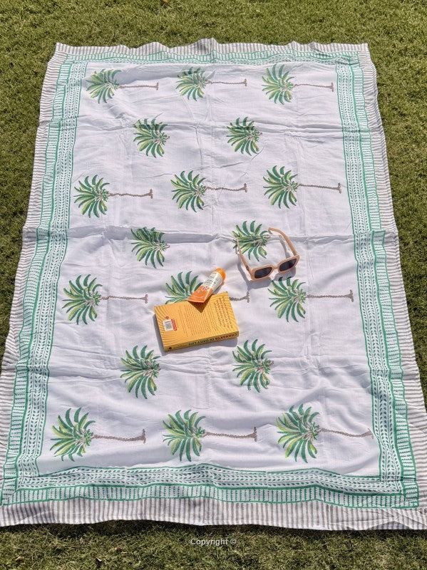 White blanket with green leaf pattern on grass