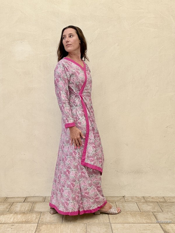 Woman wearing a pink floral dress with a matching jacket against a beige wall.