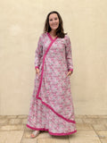 Woman wearing a pink floral dress with a matching jacket against a beige wall.
