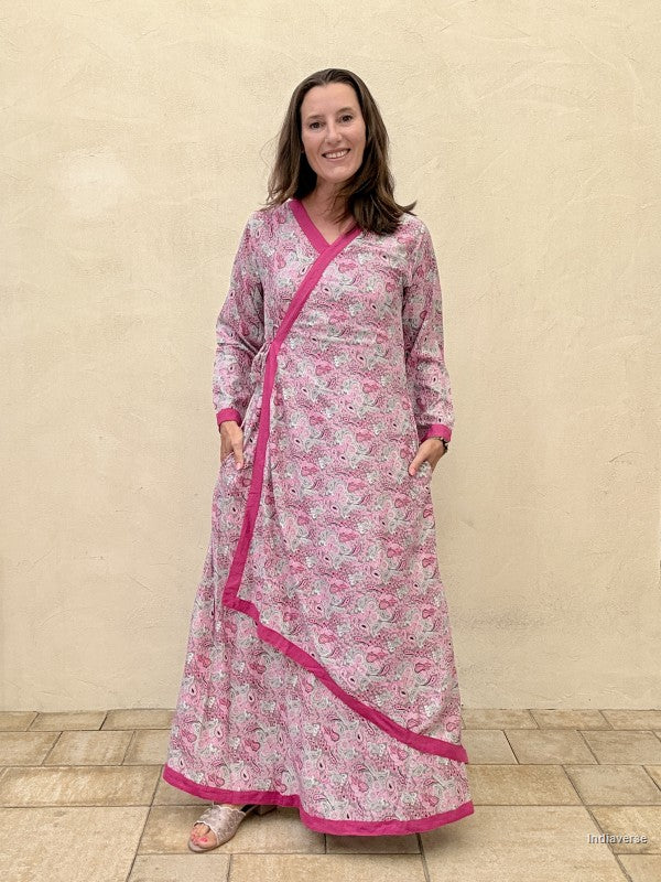 Woman wearing a pink floral dress with a matching jacket against a beige wall.
