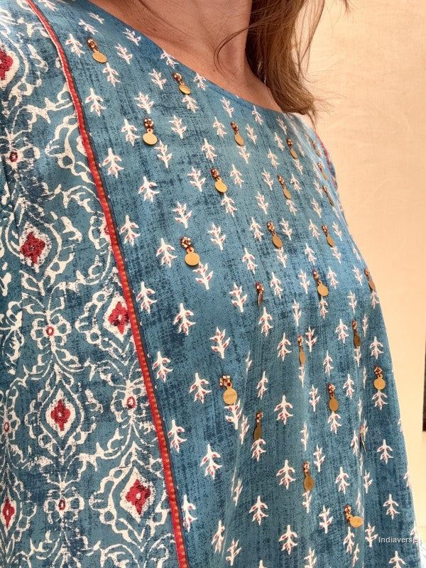 Close-up of a blue embroidered garment with white patterns and red accents.