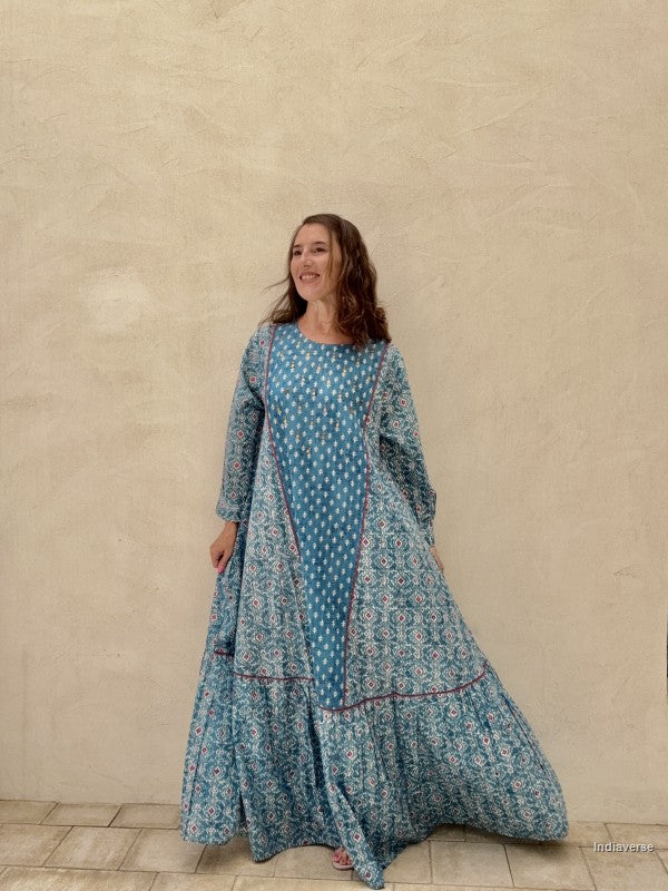 Woman wearing a blue floral dress against a beige wall.