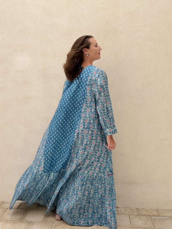 Woman wearing a blue floral dress against a beige wall