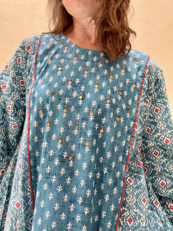 Person wearing a blue patterned dress with a beige background