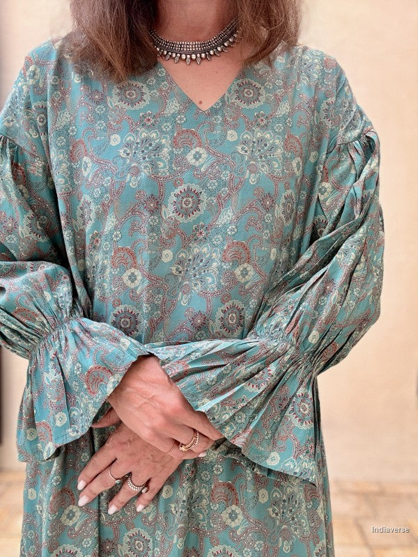 Woman wearing a patterned dress with long sleeves against a beige background