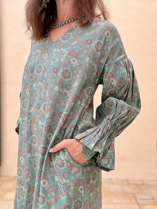 Woman wearing a floral patterned dress with long sleeves against a beige background