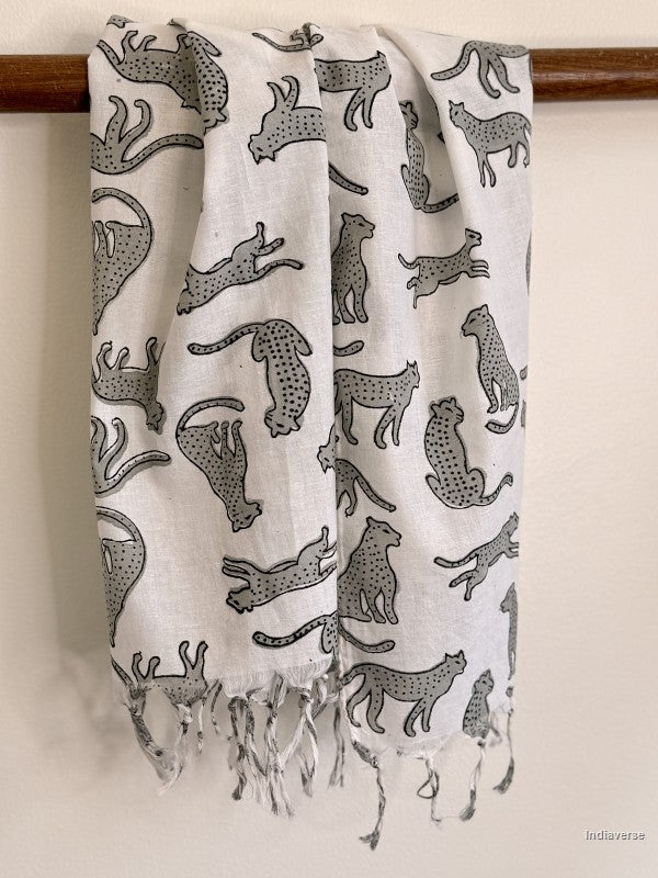 White scarf with black animal pattern hanging on a wooden rod.