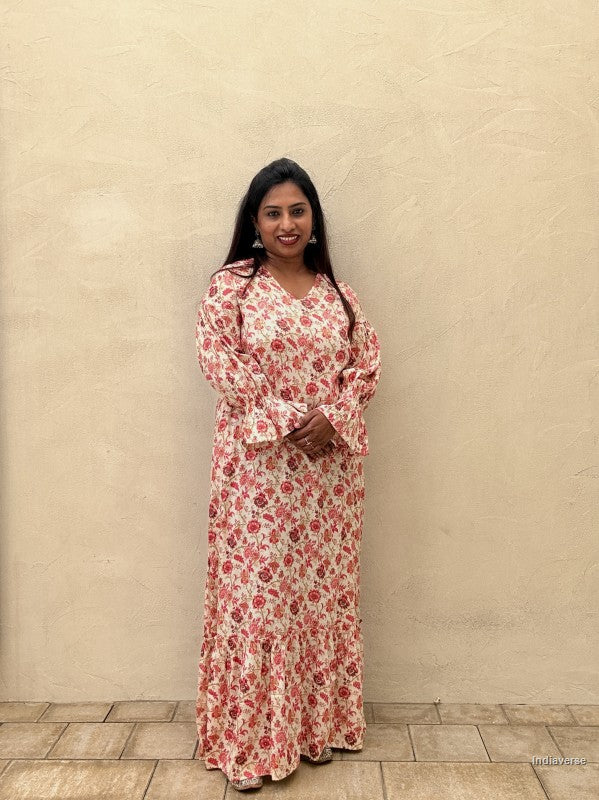 Woman wearing a floral dress standing against a beige wall.