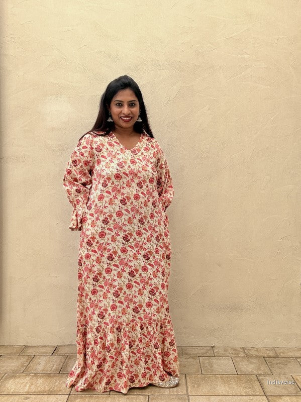 woman wearing a red floral long dress standing in front of a beige wall