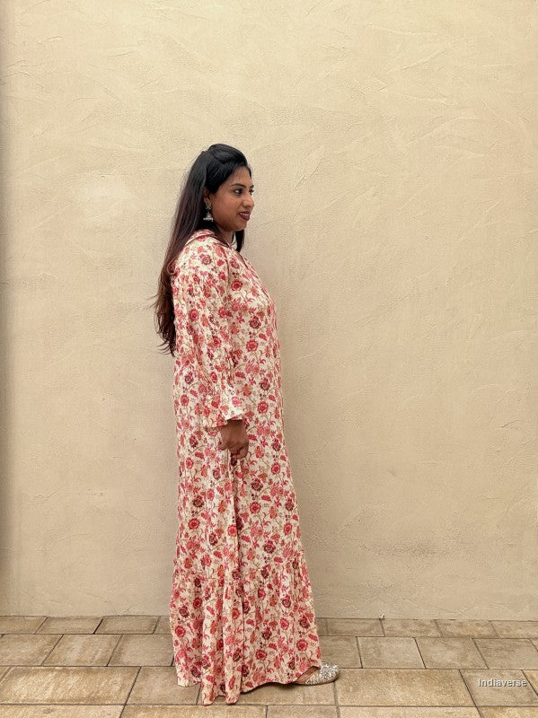 Woman wearing a floral dress standing against a beige wall.