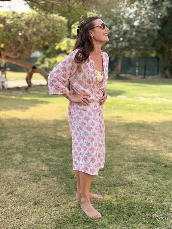 Woman in a floral dress standing on grass with trees in the background