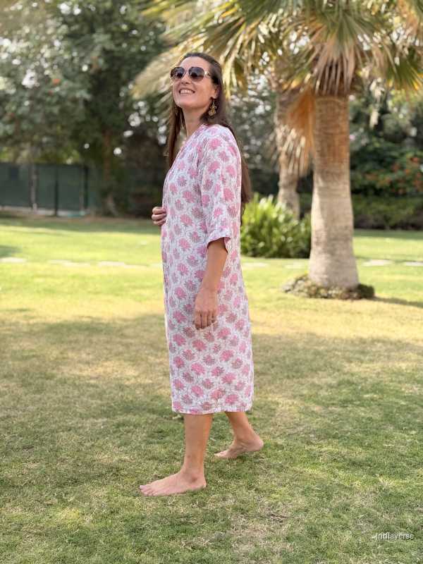 Woman in a floral dress standing on grass with trees in the background