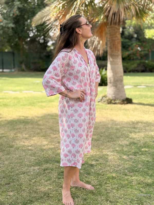 Woman wearing a floral dress standing on grass with palm trees in the background