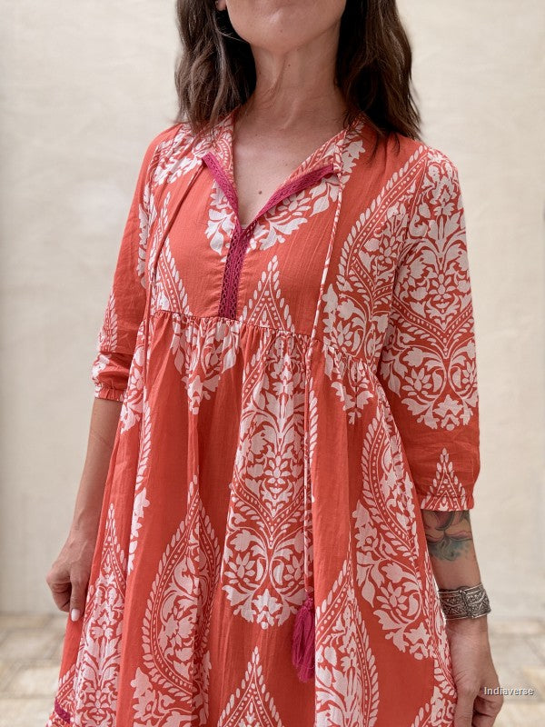 Woman wearing a red and white patterned dress against a neutral background
