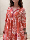 Woman wearing a red and white patterned dress against a neutral background