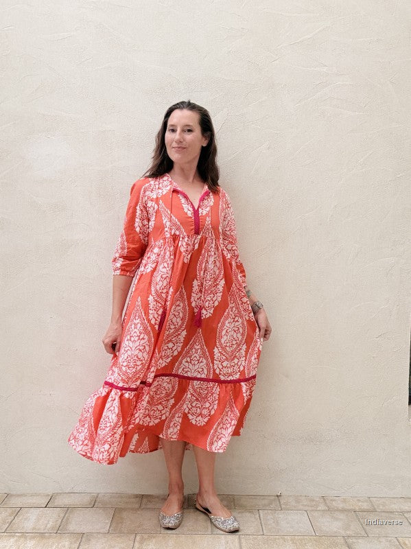 Woman wearing a red and white patterned dress against a beige wall.