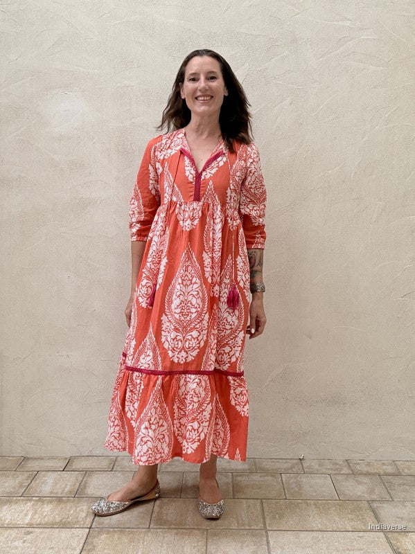 Woman wearing a red and white patterned dress against a beige wall.