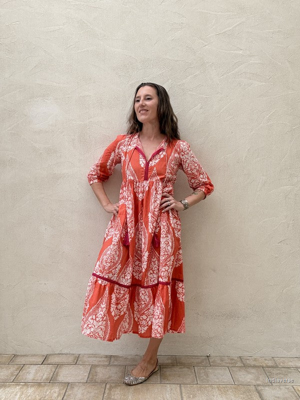 Woman wearing a red and white patterned dress against a beige wall.