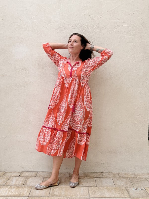 Woman wearing a red and white patterned dress against a beige wall.