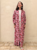 woman wearing a bolt floral abaya robe in front of a beige wall