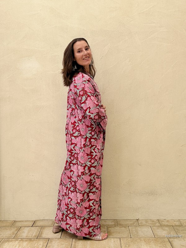 Woman wearing a pink floral dress against a beige wall.