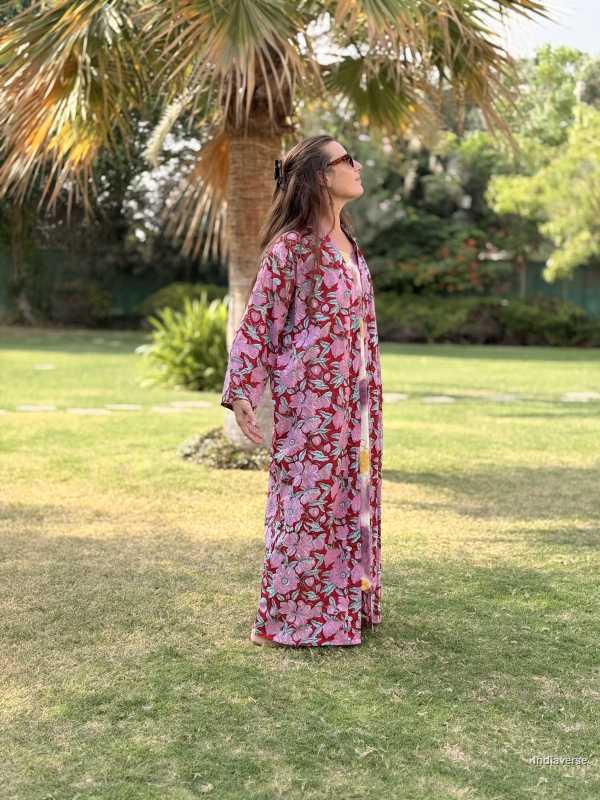 Woman in a floral dress standing on grass with palm trees in the background