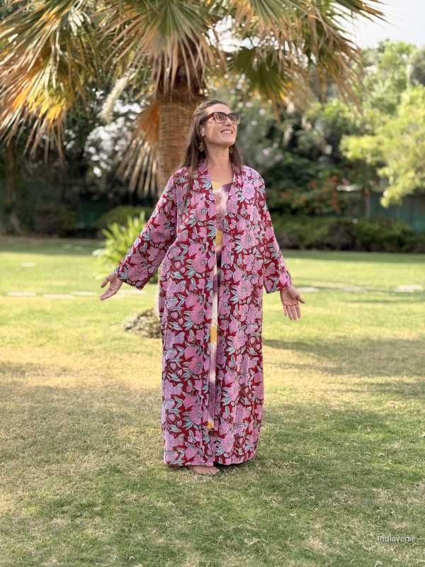 Woman in a floral dress standing in a garden with palm trees.