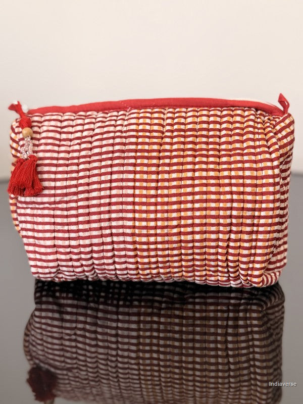 Red and white striped pouch with tassels on a reflective surface