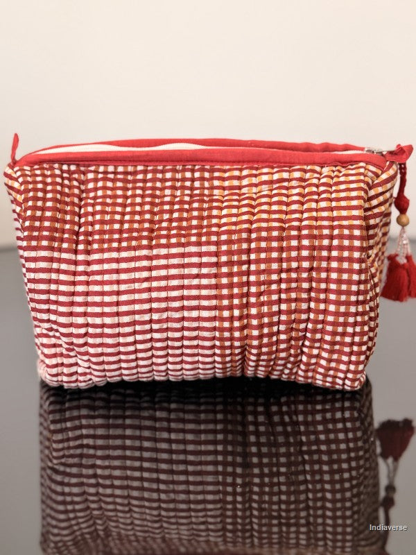 Red and white checkered pouch with a red zipper on a reflective surface.