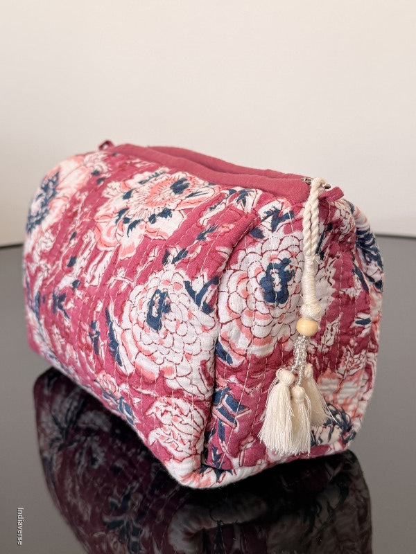 Pink floral-patterned bag with tassels on a reflective surface