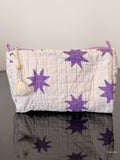 White pouch with purple star patterns on a reflective surface