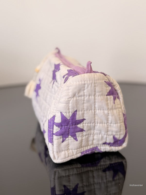 White quilted bag with purple star patterns on a reflective surface