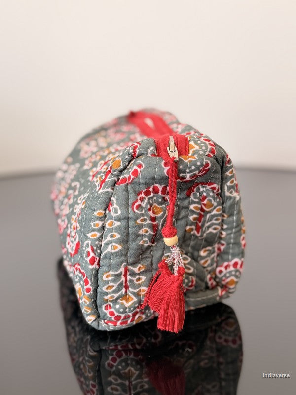 Decorative bag with a red tassel on a reflective surface