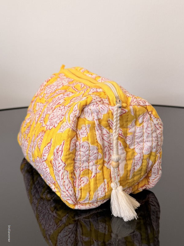 Yellow and pink patterned fabric with tassels on a neutral background