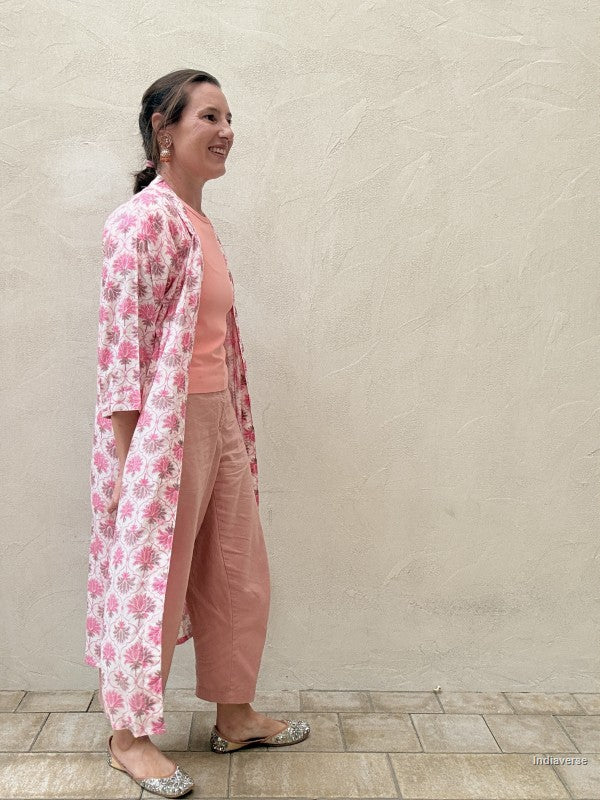 woman wearing a midi size kimono with orange lotus print standing against a beige wall